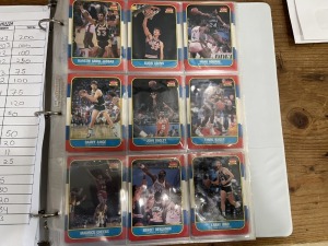 FLEER 1986 BASKETBALL BINDER - 125 OF 132 CARDS (MISSING CARDS: #7 BARKLEY / #26 DREXLER / #32 EWING / #57 JORDAN / #68 KARL MALONE / #82 OLAJUWON / #121 D WILKINS) - MAJORITY OF CARDS WOULD GRADE AT 6, 7 & 8 --- 10 OF 11 STICKERS (MISSING STICKER #8 JORD